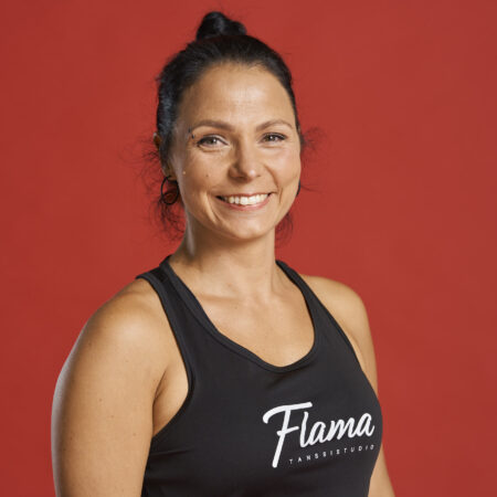 Tummahiuksinen nainen hymyilee vienosti kameralle. Päällään musta toppi, jossa lukee Tanssistudio Flama. Kuvassa Juulia Niemi.